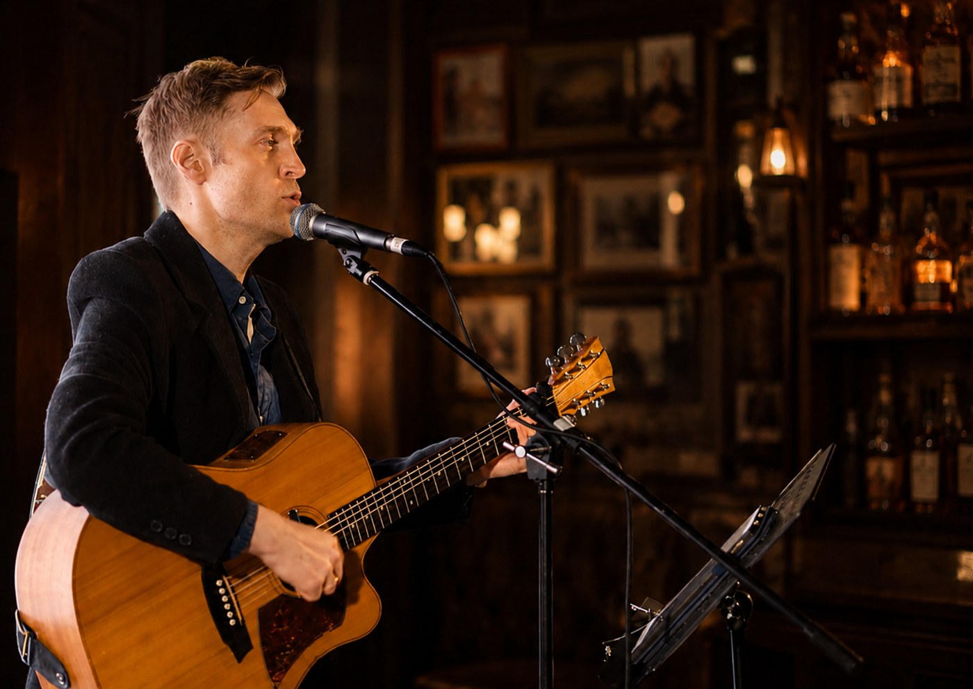Robert Rosina singing and playing acoustic guitar in a warmly lit venue